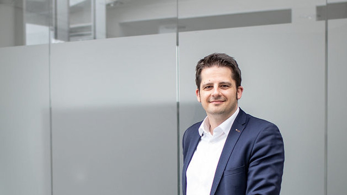 Person mit blauem Blazer vor Glaswand