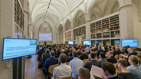 Blick in den großenTagungsraum der Göttinger Paulinerkirche.. Er ist angefüllt mit Menschen. Links und rechts stehen Monitore.