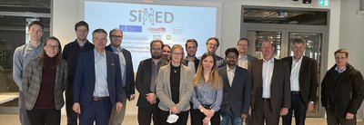 Eine Gruppe von Personen stehen nebeneinander vor einer Leinwand