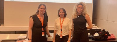 Drei Personen stehen nebeneinander vor einer Projektionsfläche