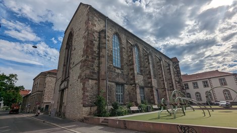 Außenansicht eies Gebäudes mit gotischen Fenstern und bewachsener Fassade.