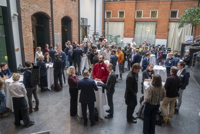 Menschen an Stehtischen in einem Atrium im Gespräch