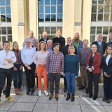 Menschen vor einem Gebäude mit gelber Fassade 