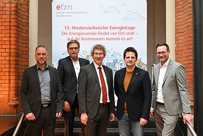 Eine Gruppe von Personen stehen nebeneinander und haben hinter sich ein Plakat