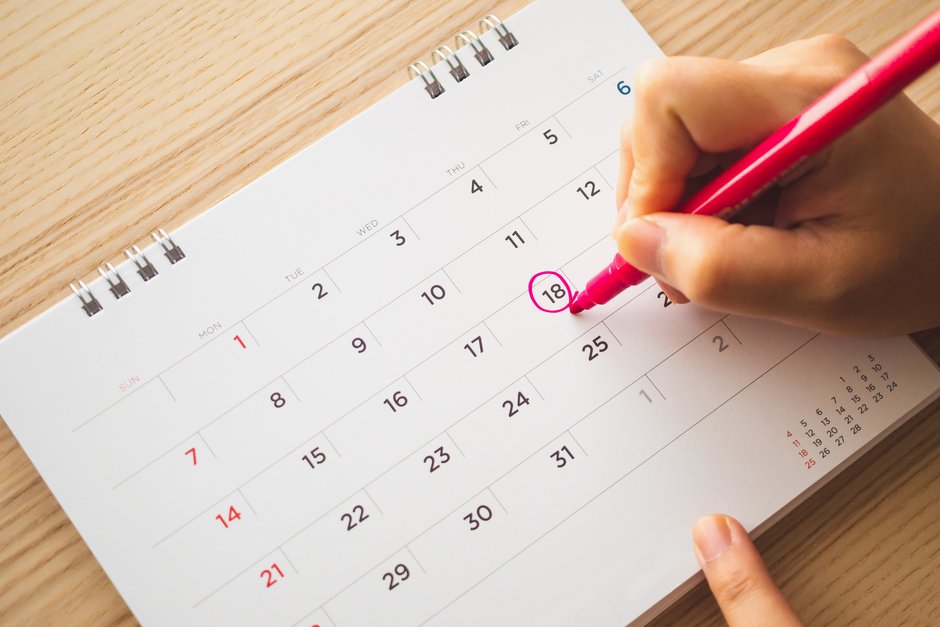 Auf einem Monatskalender umkreist eine Hand mit Filzstift einen bestimmten Tag