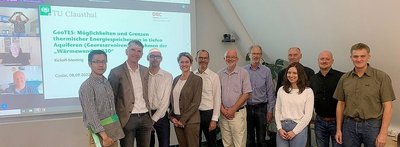 Eine Gruppe von Personen stehen nebeneinander vor einer Leinwand