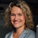 Eine Frau mit lockigen Haaren lächelt