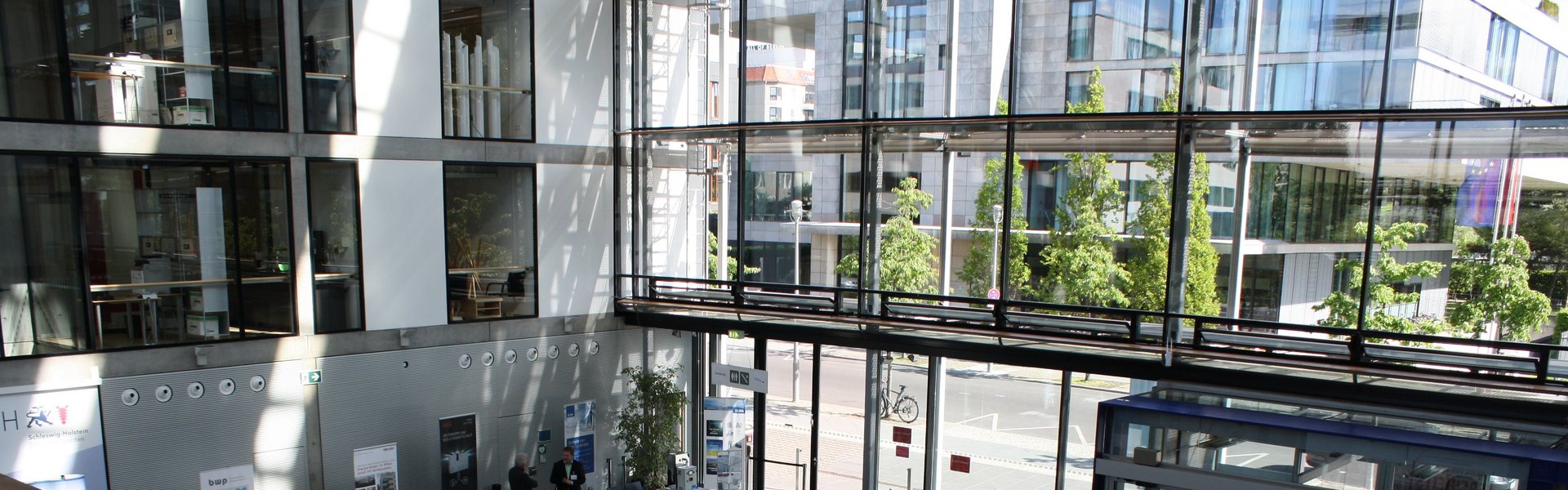 Blick durch eine Fensterfront auf ein modernes Gebäude.