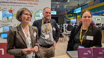 Zwei Frauen und ein Mann an einem Messestand