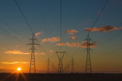Freileitungsmasten mit der untergehenden Sonne im Hintergrund