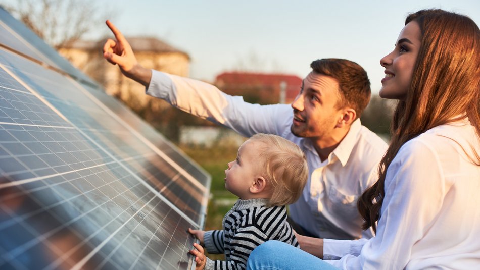 Eine Familie vor einem Dach mit Solarpanels