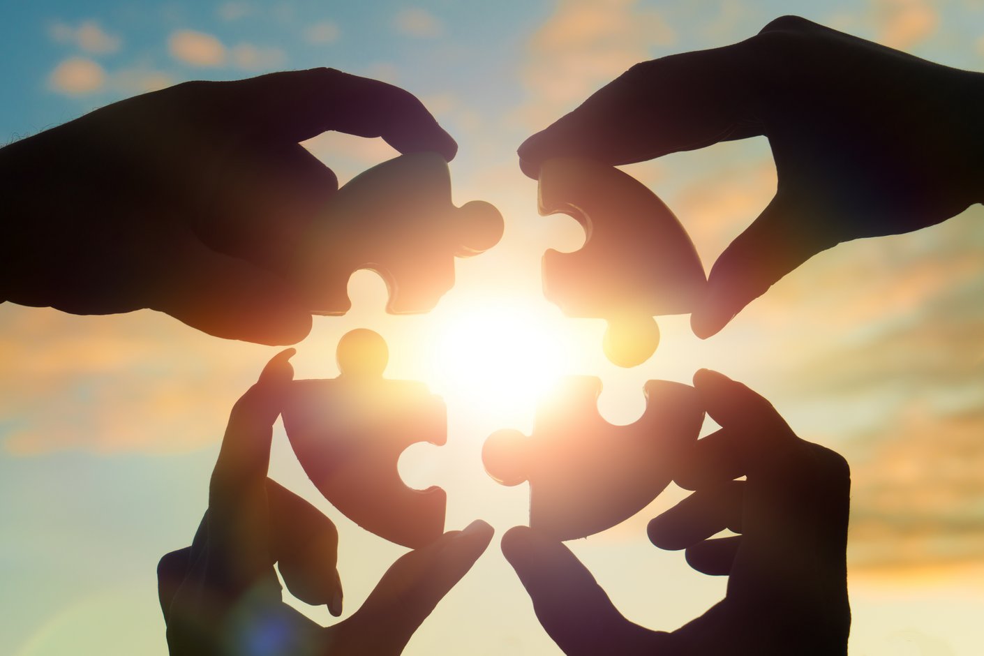 Hände, die vor der Sonne Puzzleteile zusammensetzen
