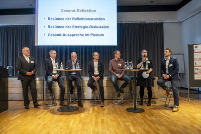 Männer und Frauen vor einer Leinwand