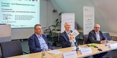 Drei Personen an einem Tisch halten eine Präsentation