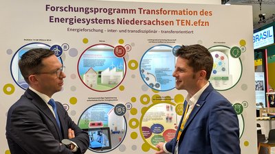 Zwei Männer vor einem Messeexponat mit runden Blicklöchern
