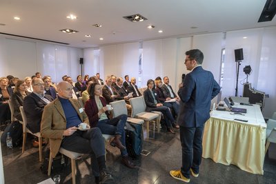 Ein Mann steht vor sitzenden Menschen und redet